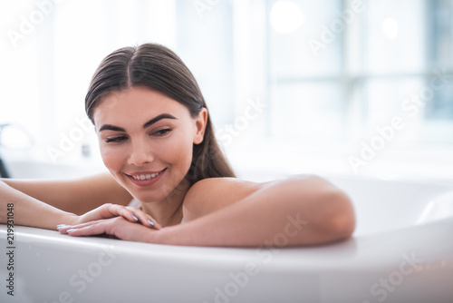 Portrait of glad woman with attractive smile and wet hair having leisure in cozy bathroom