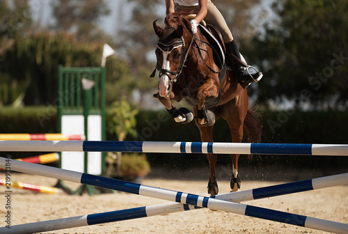 Dżokej na koniu skacze przez przeszkodę, przeskakując przeszkodę podczas zawodów