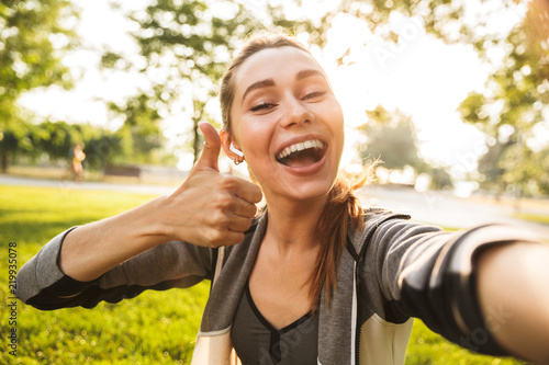 Fotografija Photo of feminine fitness girl 20s in sportswear wearing bluetooth earpod taking