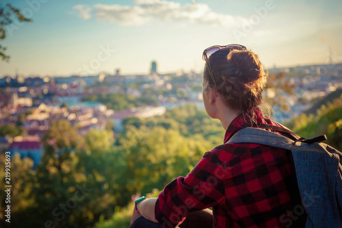 Young traveler woman tourist looking at a European city at sunset from a height, travel atmosphere, Vilnius, Lithuania