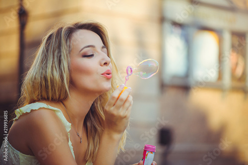 happy gentle woman with soap bubbles summer warm day, dressed in light dress