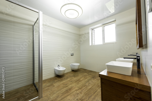 interior of modern bathroom with glass shower  toilet  bidet and two sinks