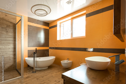 interior of bathroom in orange and white colors with bathtube  sink and bidet
