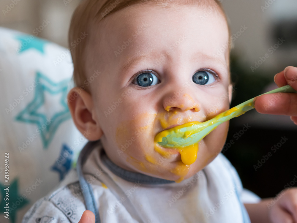 Adorable baby boy with blue eyes eating lunch Adorable baby boy with blue eyes eating lunch