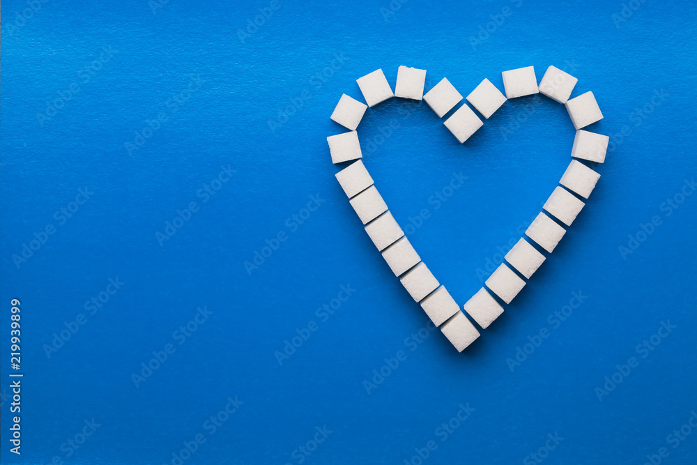 Obraz premium Heart made of cubes of sugar. blue background.
