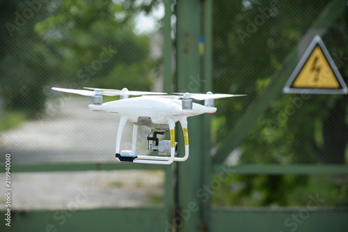Quadcopter flying, fence with a high-voltage sign on a background.  July 10, 2018. Kiev, Ukraine