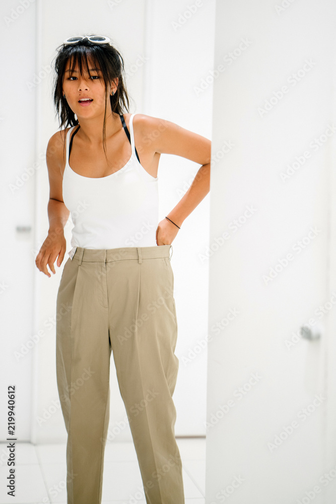 Portrait of a young, skinny and attractive Asian teenager trying on a new pair of pants in the fitting room. Portrait of a young, skinny and attractive Asian teenager trying on a new pair of pants in the fitting room.