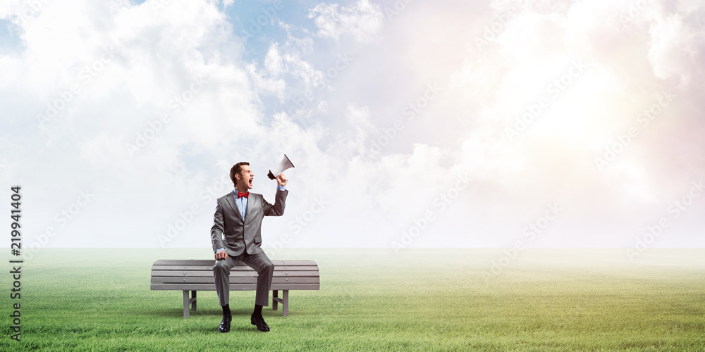 Businessman in summer park announcing something in loudspeaker