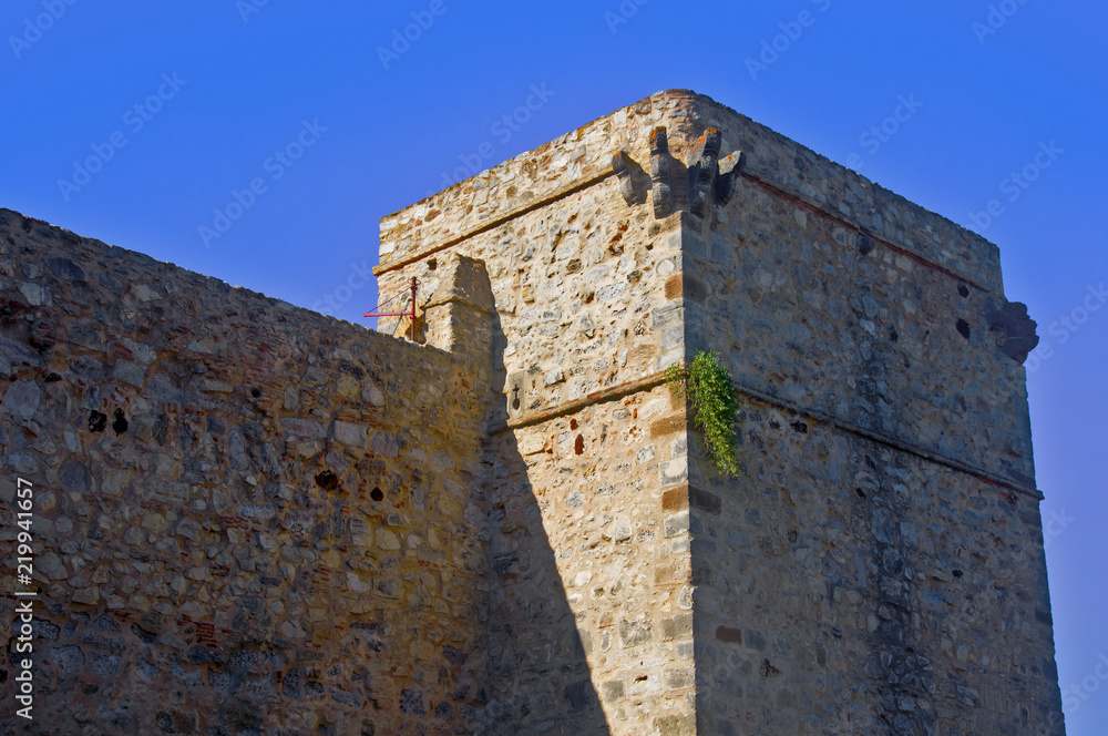 Rectangular grey tower and wall, blue sky, summer