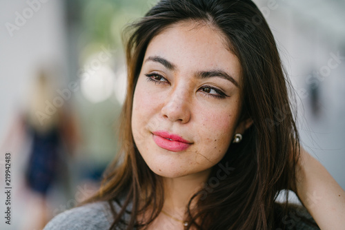 A close up photo of a young Japanese Asian woman. She is smiling casually and has a pretty face.