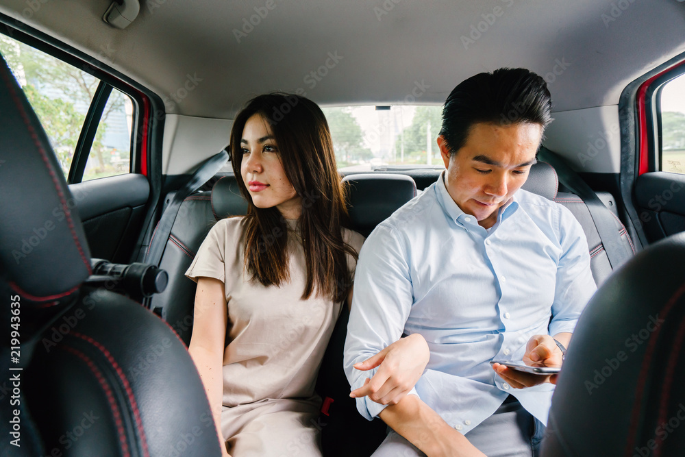 A young attractive Japanese woman leans toward her boyfriend as they ride a car which they booked from a ride hailing app. She is tired yet happy from their trip. A young attractive Japanese woman leans toward her boyfriend as they ride a car which they booked from a ride hailing app. She is tired yet happy from their trip.