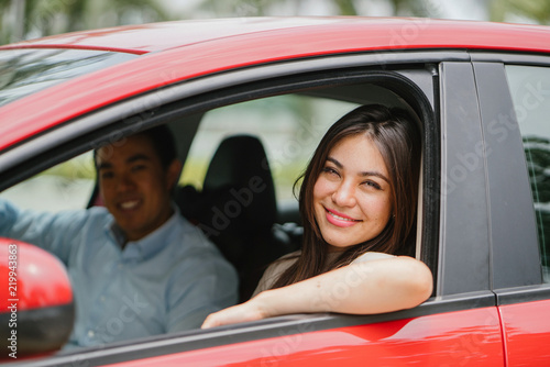 Photography Portrait of a young Japanese Asian woman leaning out the window of a red car window and smiling happily