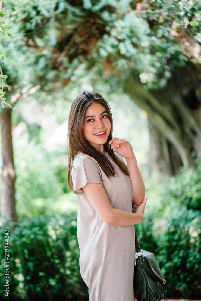 A young attractive Japanese Asian woman strikes a pose as she strolls in the park. She looks happy and comfortable in her element. A young attractive Japanese Asian woman strikes a pose as she strolls in the park. She looks happy and comfortable in her element.