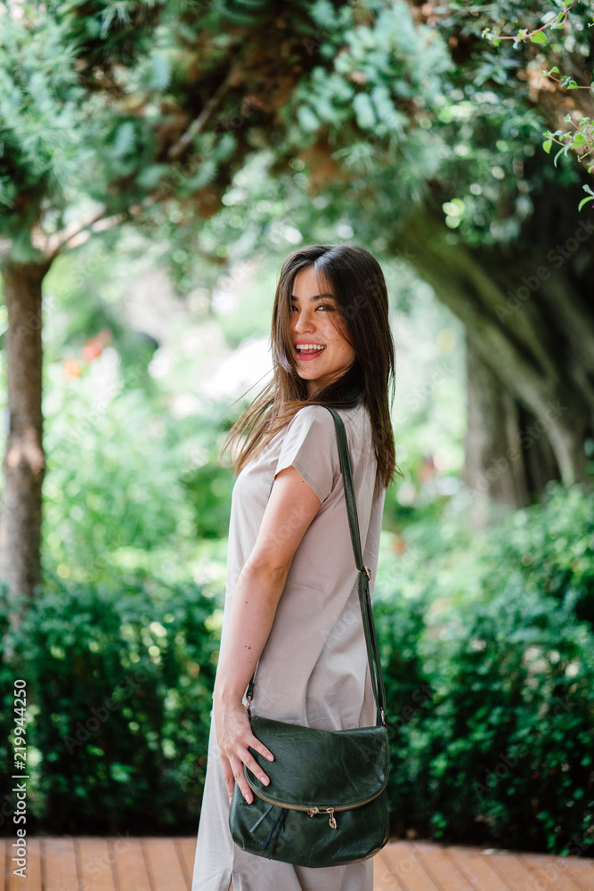 A young attractive Japanese Asian woman strikes a pose as she strolls in the park. She looks happy and comfortable in her element. A young attractive Japanese Asian woman strikes a pose as she strolls in the park. She looks happy and comfortable in her element.