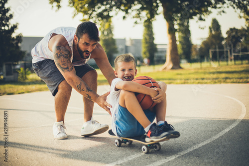 Father pushing his son on skateboard.