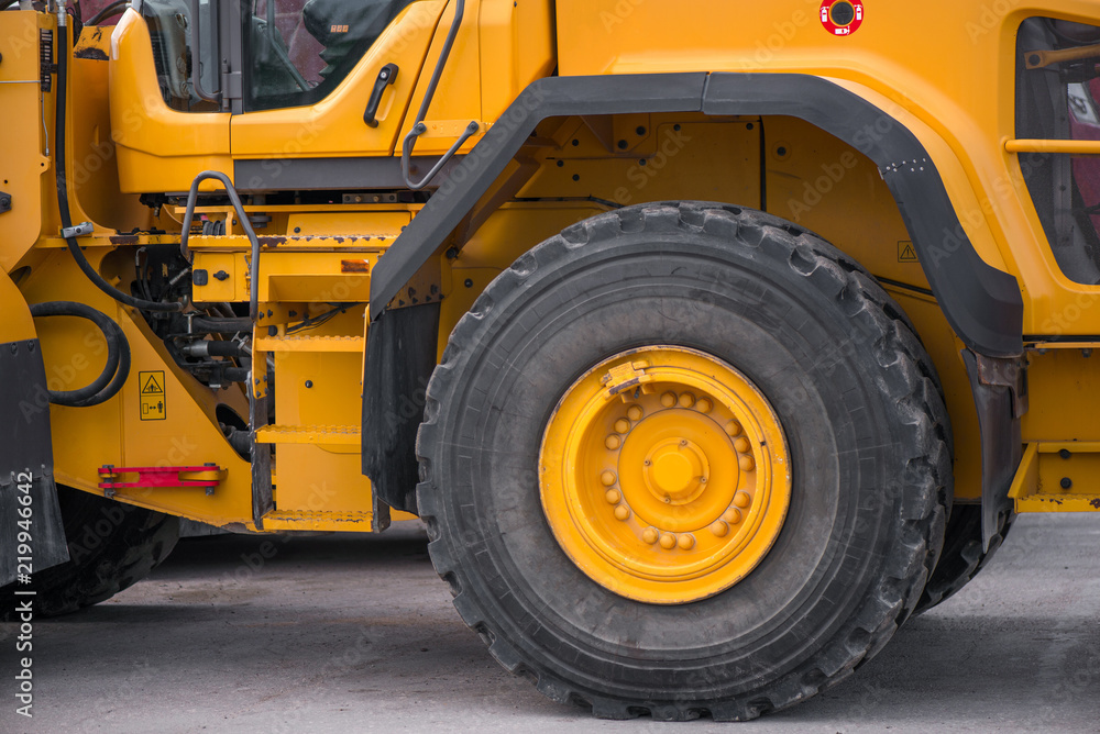 Macro shot of frontal excavator tire. Construction machinery in large parking lot in industrial territory  
