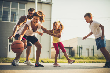 Happy family playing basketball. Spring season.