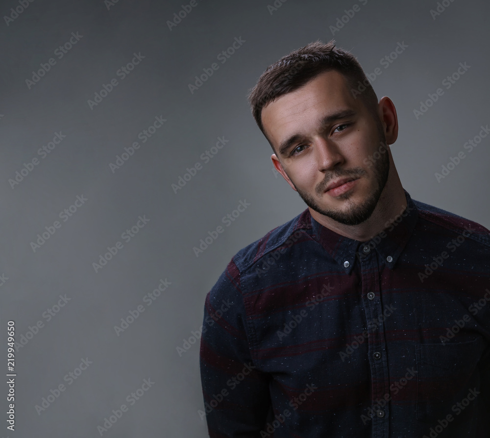 Fototapeta premium Young man studio shot portrait. Handsome in checkered shirt. Copy space dark grey background