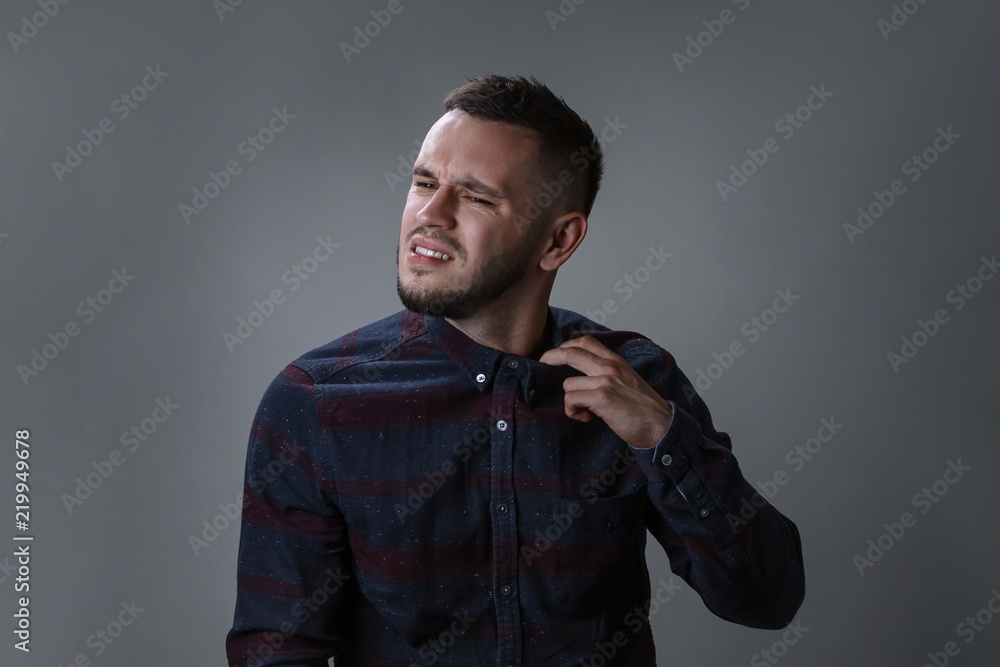 Fototapeta premium Tired young bearded man taking off collar, removing his tie on dark grey background