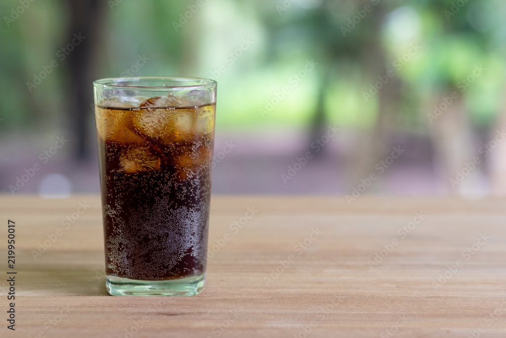 Refreshing black soda soft drinks or cola with ice in a clear tall glass with nature background. Refreshing black soda soft drinks or cola with ice in a clear tall glass with nature background.