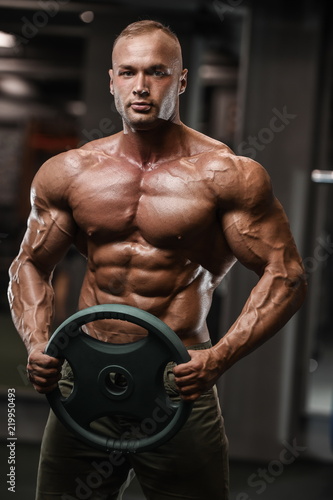 Handsome strong bodybuilder athletic men pumping up muscles with dumbbells