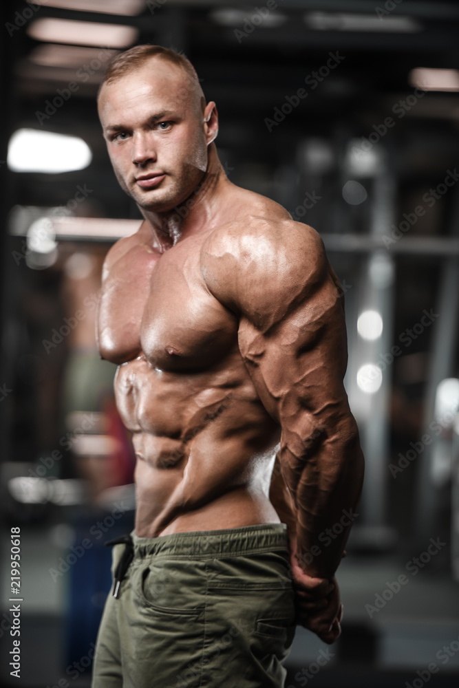 Handsome strong bodybuilder athletic men pumping up muscles with dumbbells Handsome strong bodybuilder athletic men pumping up muscles with dumbbells