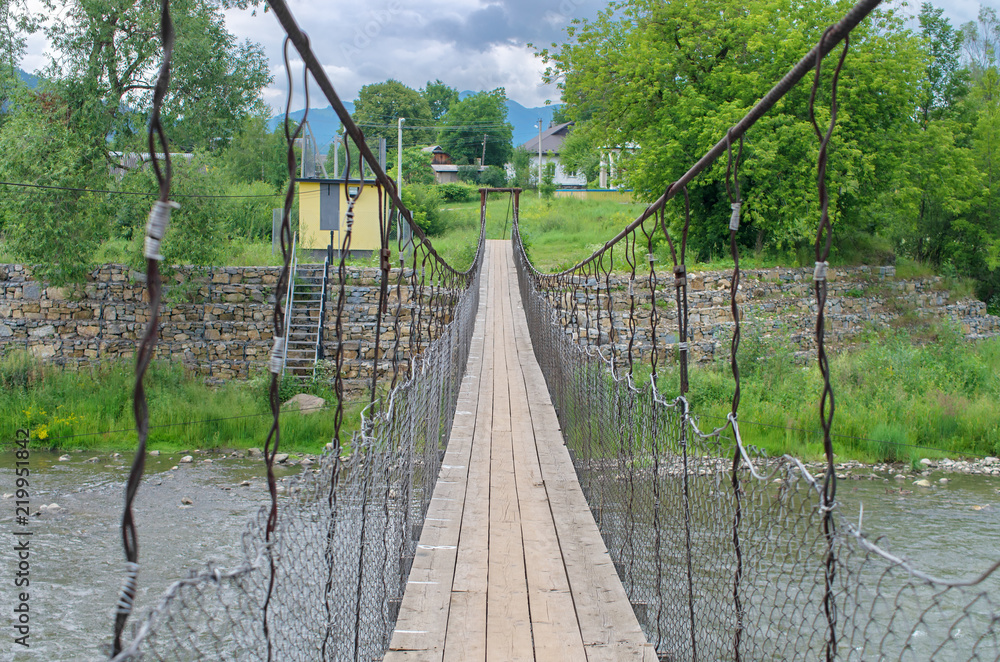 Obraz premium Suspension bridge across the mountain river. Carpathians Ukraine