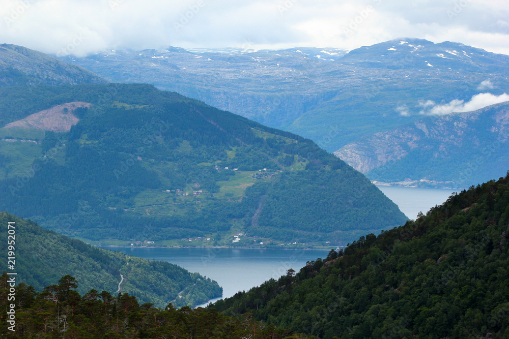 View of Husedalen valley with cascade of four waterfalls and Kinsarvik fjord, Norway