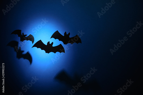 Black paper bats flying on dark blue background. Halloween concept. Paper cut style.