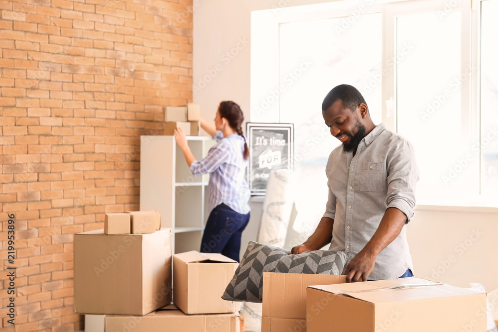 Interracial couple with carton boxes in room. Moving into new house Interracial couple with carton boxes in room. Moving into new house
