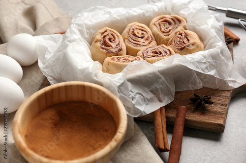 Baking dish with uncooked cinnamon rolls and ingredients on kitchen table
