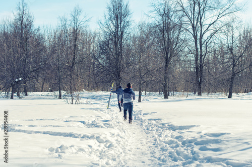 Two boys running along the path in a snowy forest
