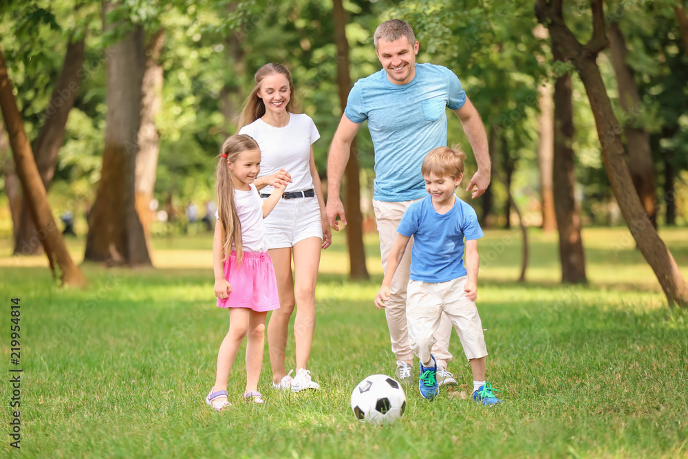 Fototapeta premium Happy family playing football in park on summer day