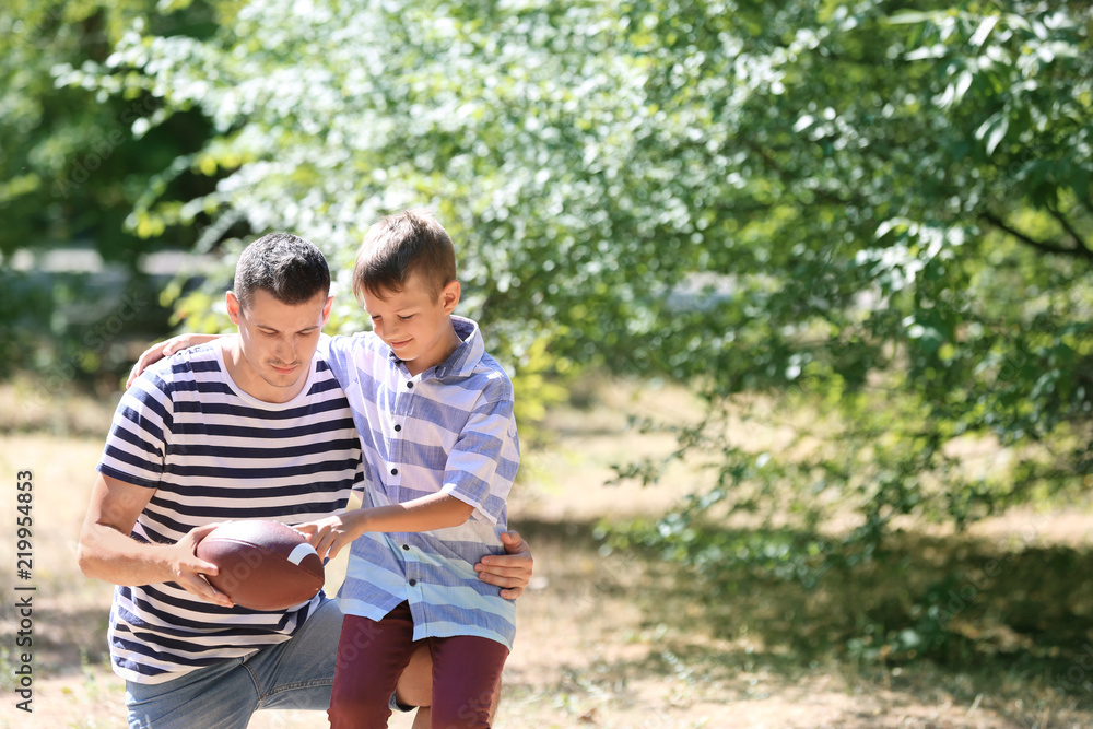 Fototapeta premium Dad and son with rugby ball outdoors