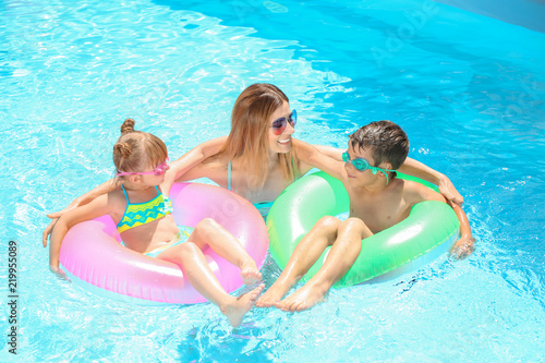 Happy mother and children with inflatable rings resting in swimming pool © Pixel-Shot