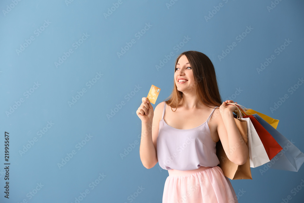 Beautiful young woman with shopping bags and credit card on color background Beautiful young woman with shopping bags and credit card on color background