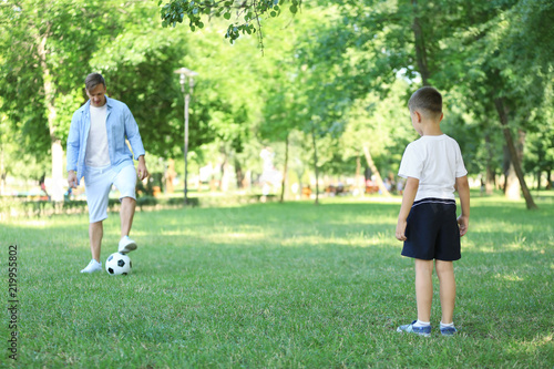 Little boy with his dad playing football in park