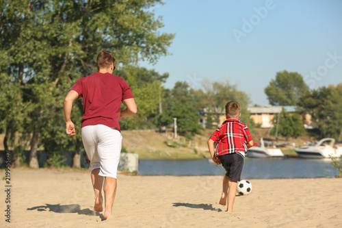 Little boy with his dad playing football on sand beach © Pixel-Shot