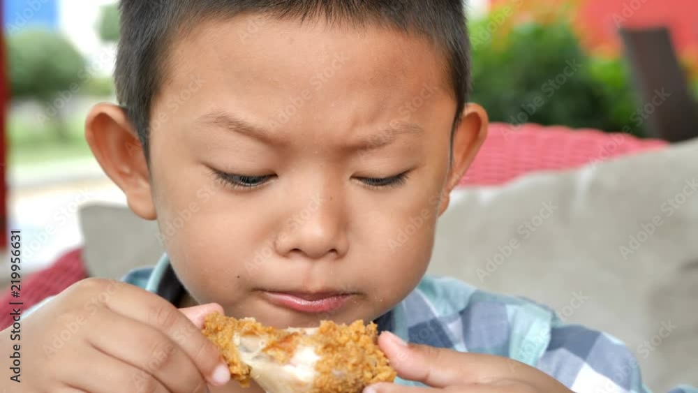 Cute asian boy are happy eating fried chicken leg in restaurant. Video 4k Slow motion Cute asian boy are happy eating fried chicken leg in restaurant. Video 4k Slow motion