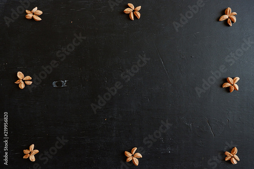 Black wooden background with a pattern. Seeds in the form of a flower on the board. Free space for design.
