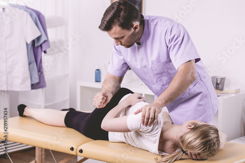 Doctor in uniform massaging woman with backbone problem