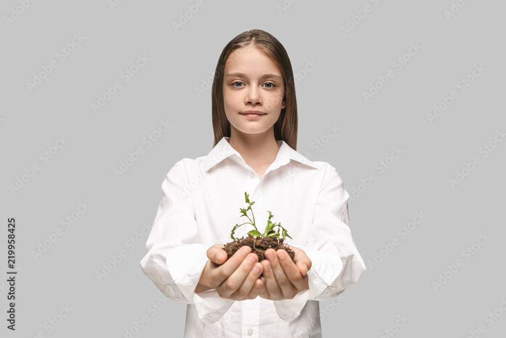 Teen hands with seedlings on studio background. Spring, plant, nature, growing and care concept. Caucasian little girl Teen hands with seedlings on studio background. Spring, plant, nature, growing and care concept. Caucasian little girl