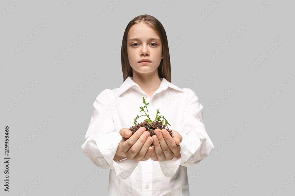 Teen hands with seedlings on studio background. Spring, plant, nature, growing and care concept. Caucasian little girl Teen hands with seedlings on studio background. Spring, plant, nature, growing and care concept. Caucasian little girl