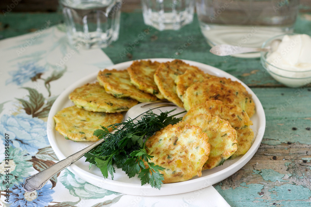 Pancakes with zucchini and sweet corn, served with sour cream, parsley and dill. Vegetarian food. Pancakes with zucchini and sweet corn, served with sour cream, parsley and dill. Vegetarian food.