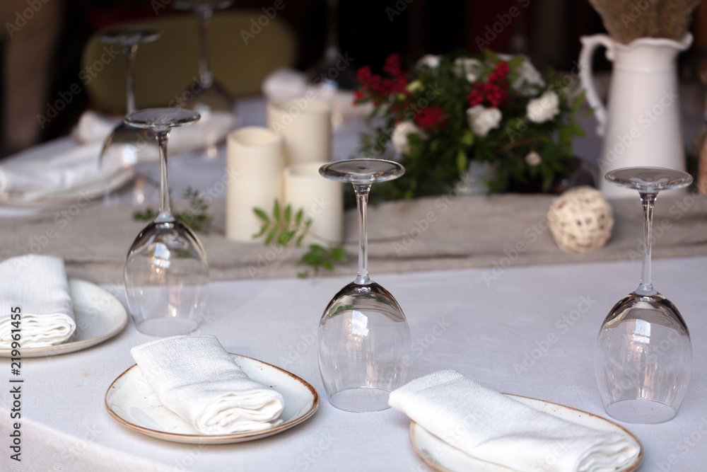 Beautifully decorated catering on bright tablecloths. Serving with glasses, plates, cutlery, flowers and a fan