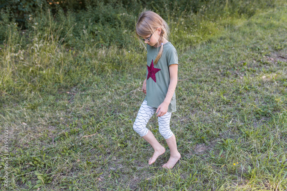 Ein 7 jahre altes Mädchen läuft barfuß auf einem Feldweg Photos | Adobe  Stock