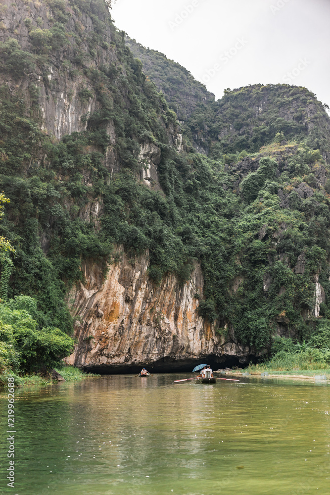 Boatride from Vung Tram Pier. Traditional paddle-boat trip lets the tourists truly appreciate the serenity and beauty of nature along the Ngo Dong River, grottoes and limestone karsts Tam Coc.