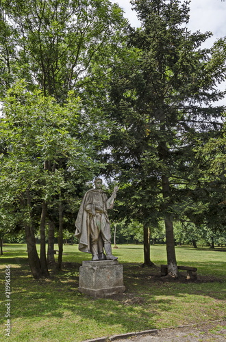 Landscape of summer nature with deciduous forest and old abandoned statue of bulgarian young man in the natural old West park, Sofia, Bulgaria 