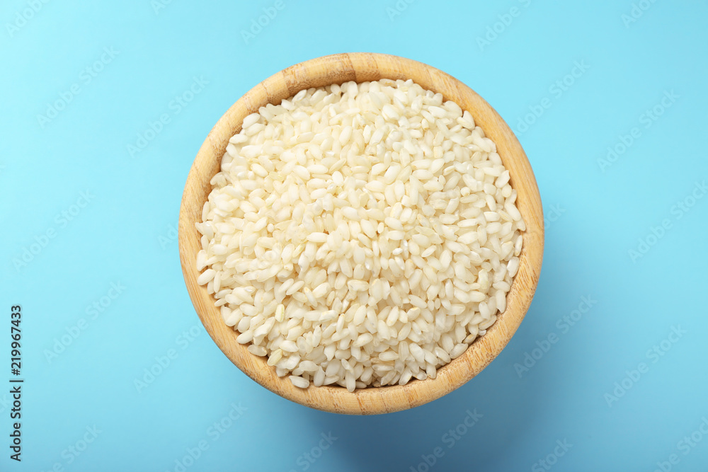 Wooden bowl with raw rice on color background Wooden bowl with raw rice on color background