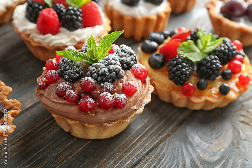 Tasty tartlets with berries on wooden table, closeup Tasty tartlets with berries on wooden table, closeup